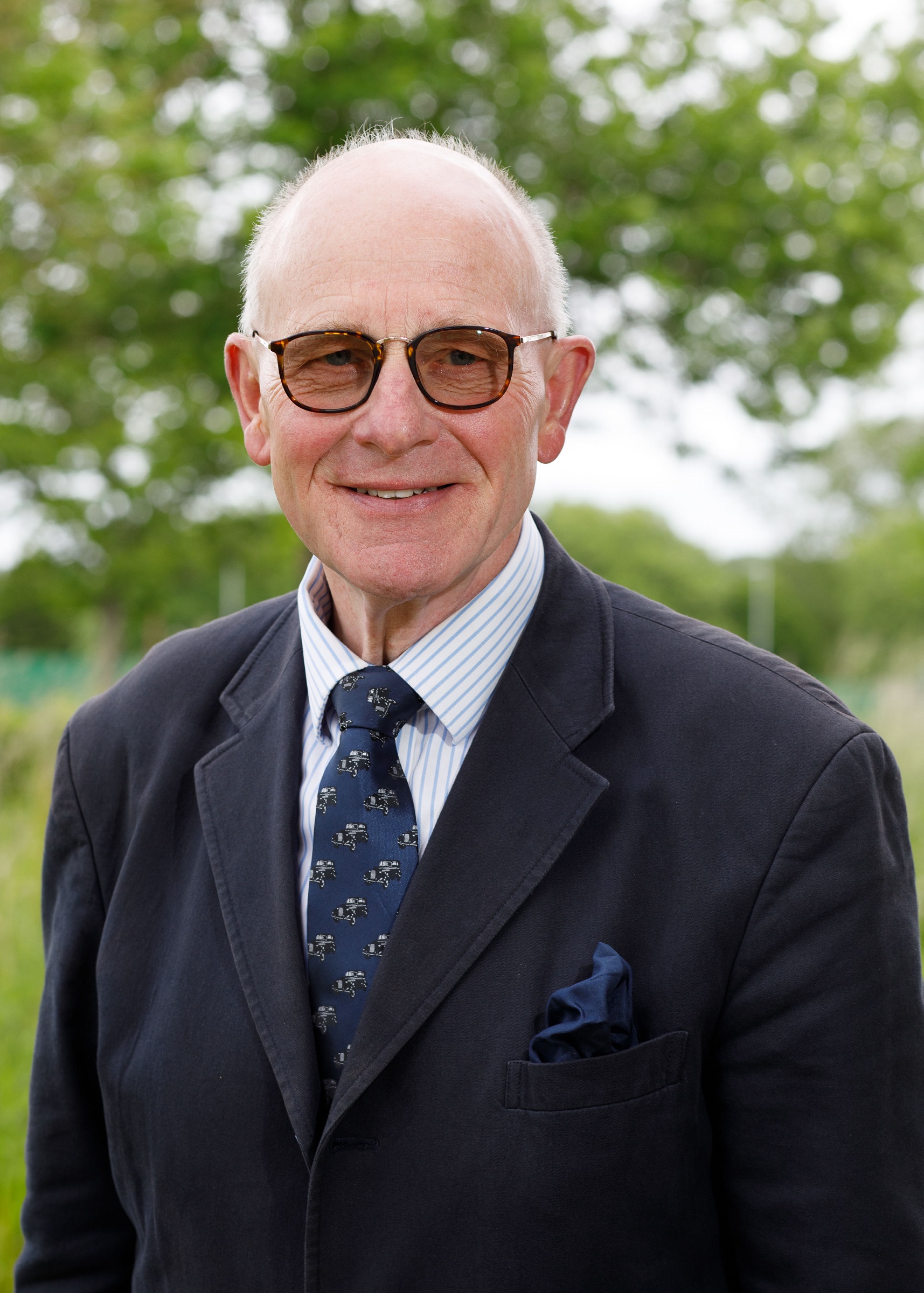 Hugh Crabtree, wearing glasses, a dark suit and tie